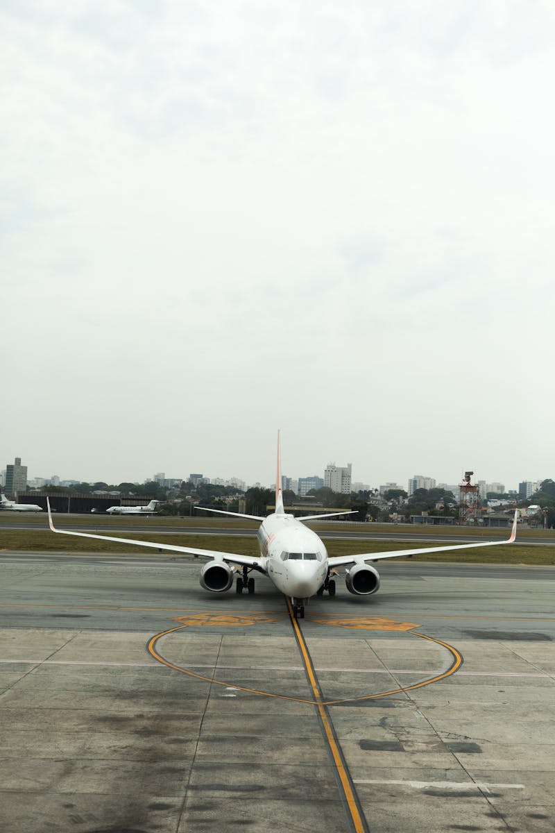 Front view of an airplane taxiing on the runway with a city skyline in the background, at Florianópolis airport.