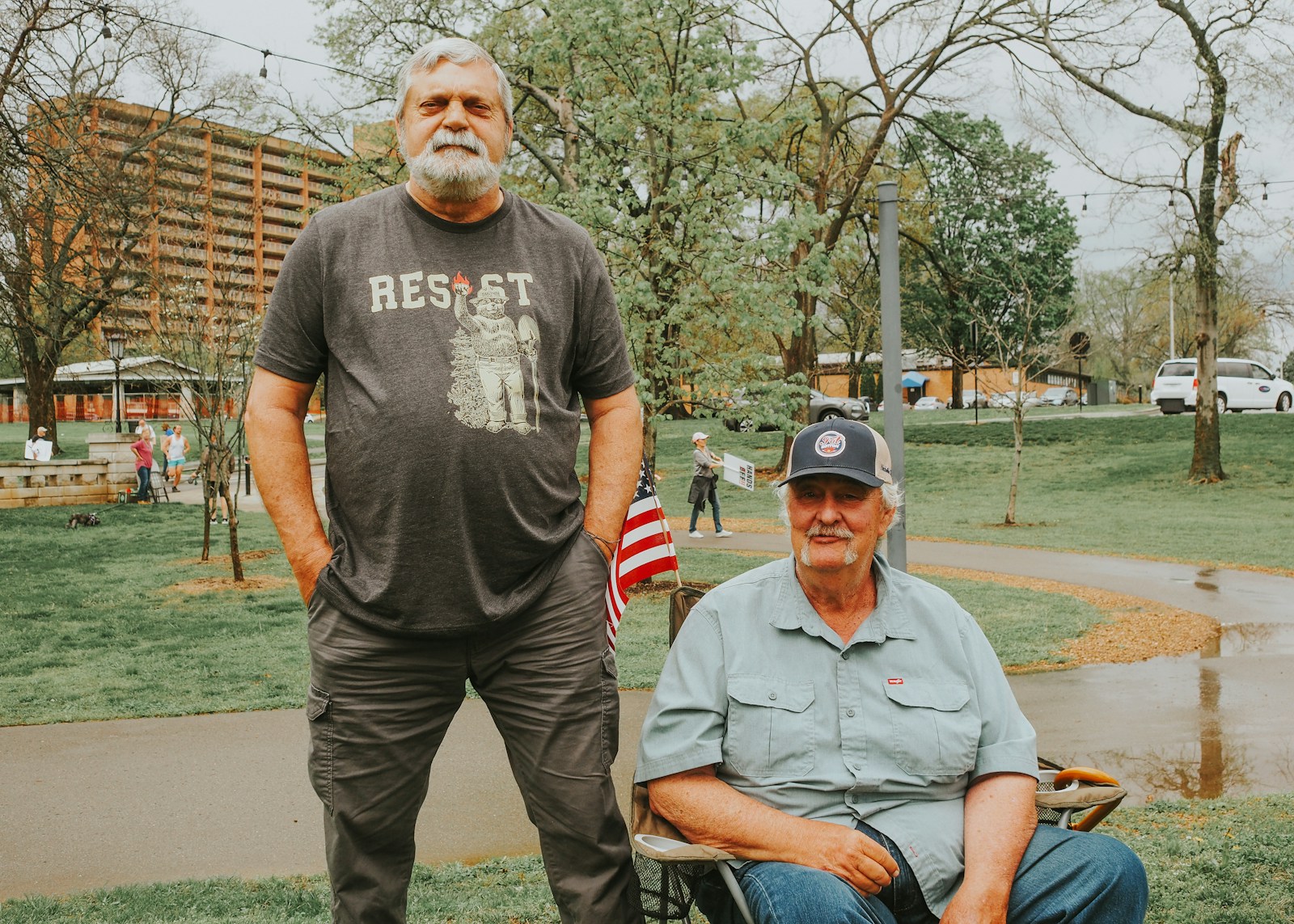 Two men pose outside on a cloudy day.