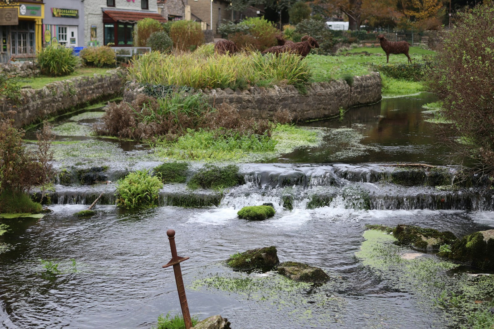 Horses graze by a river with a sword in foreground.